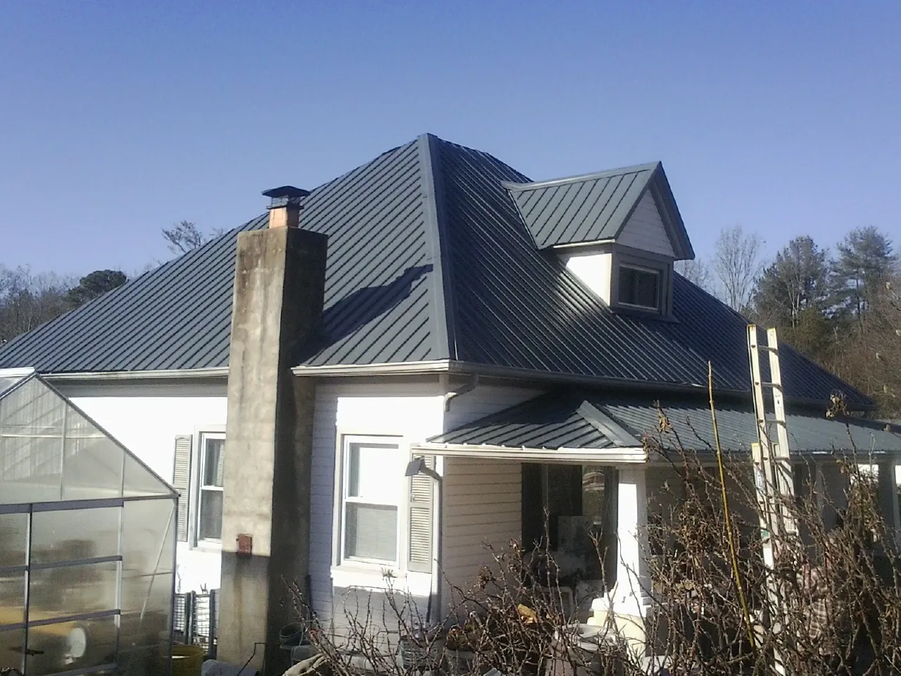 Dark blue standing seam metal roof on a white farmhouse with dormer — Slate & Tile Roof Repair by Roofing Brothers in Strasburg