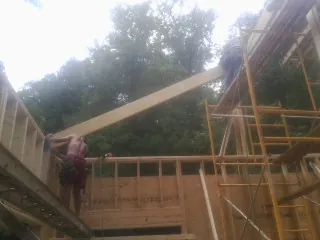 Carpenter raising a rafter beam on a new second story frame in Strasburg