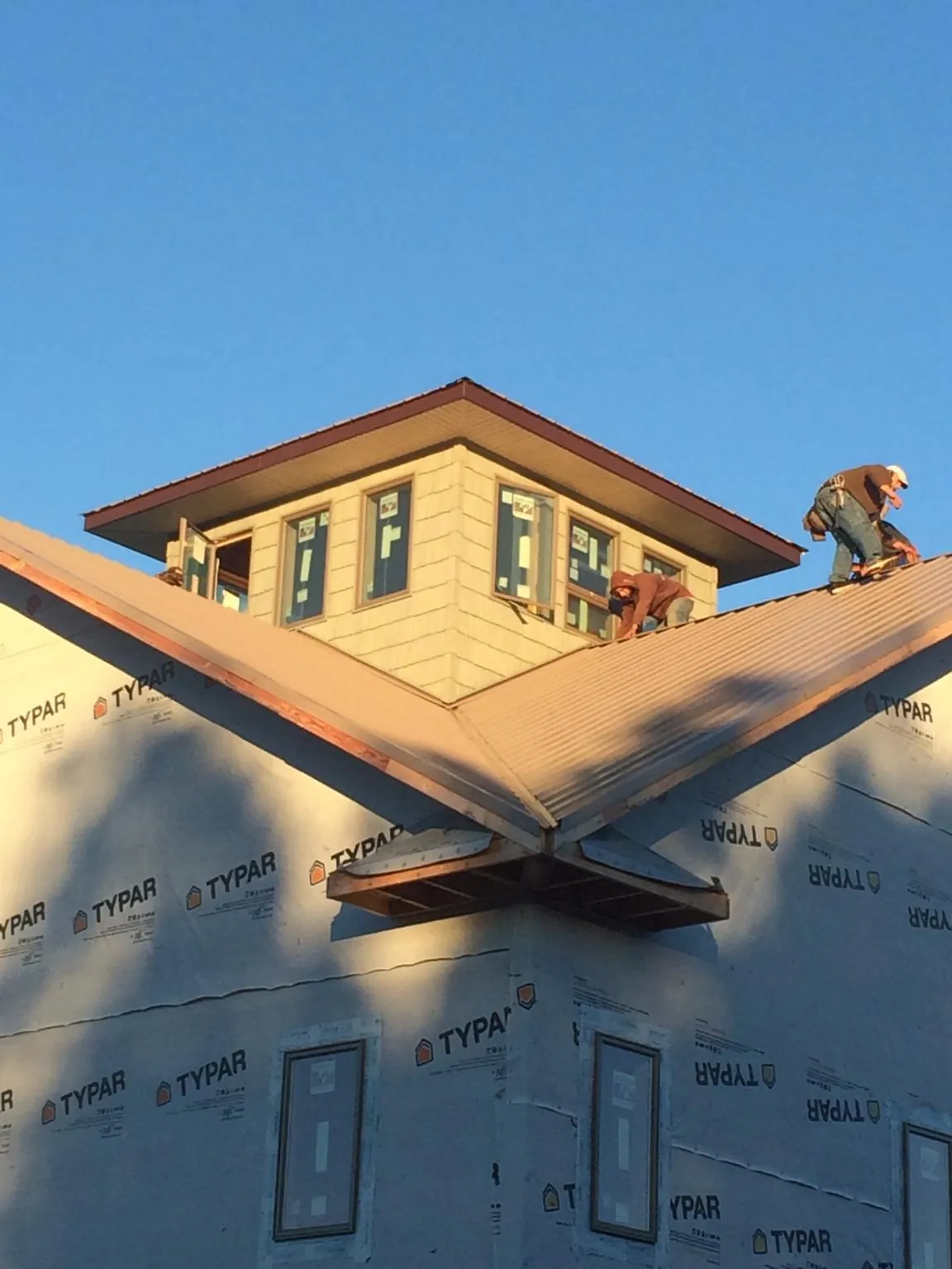 Roofers working around a rooftop cupola on a new metal roof at sunset — Roof Waterproofing in Strasburg by Roofing Brothers